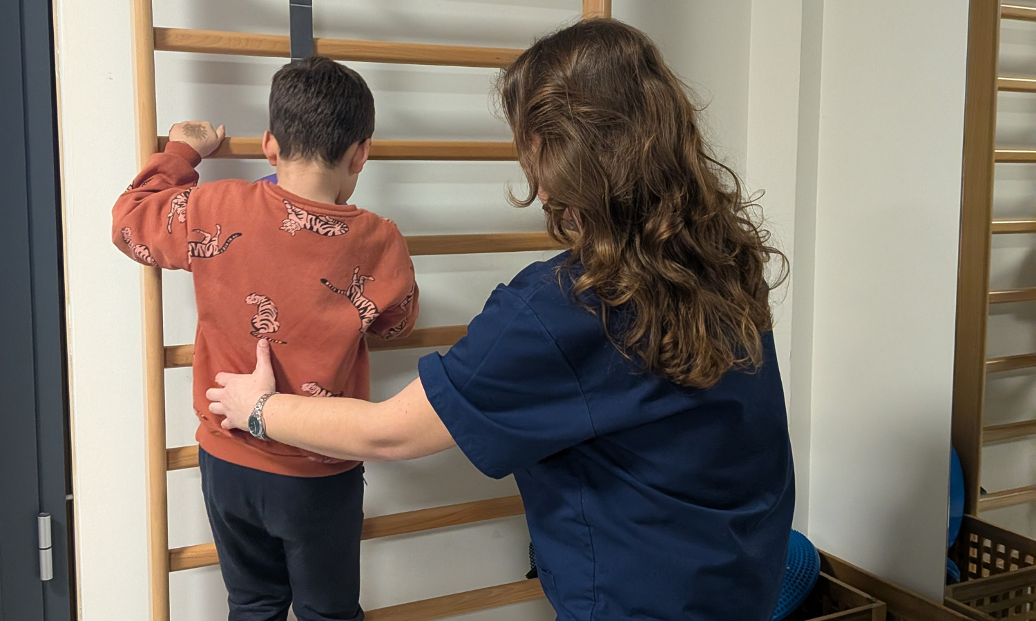 bimbo fa esercizio aiutato da fisioterapista